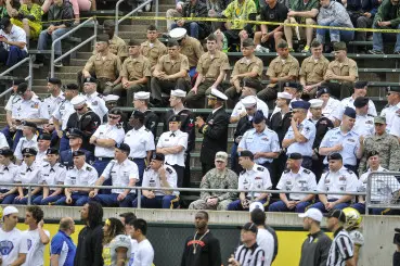Service members watch from the 50-yard line.