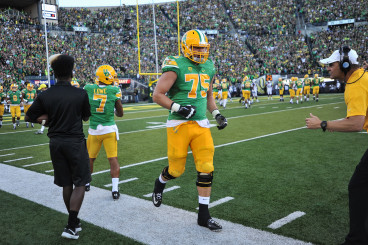 Coach Mark Helfrich applauding Fisher as he leaves the field during the Ducks win over Washington at Autzen stadium.
