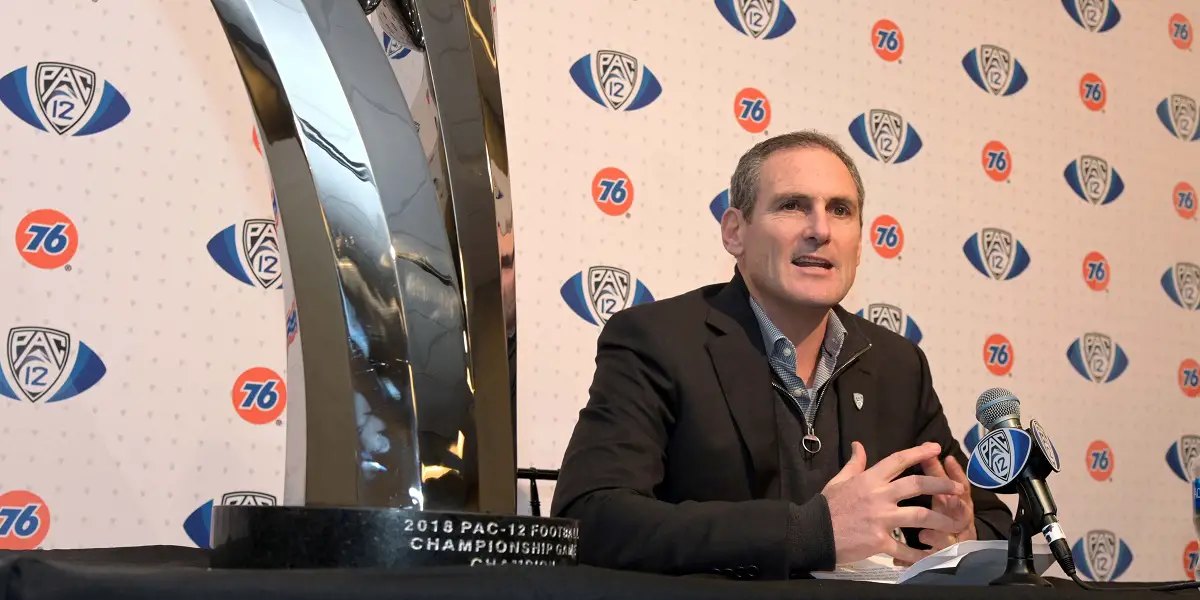 Image of Larry Scott sitting next to Pac-12 Championship trophy.
