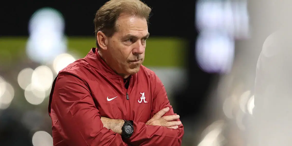 Nick Saban looks on with his arms crossed.